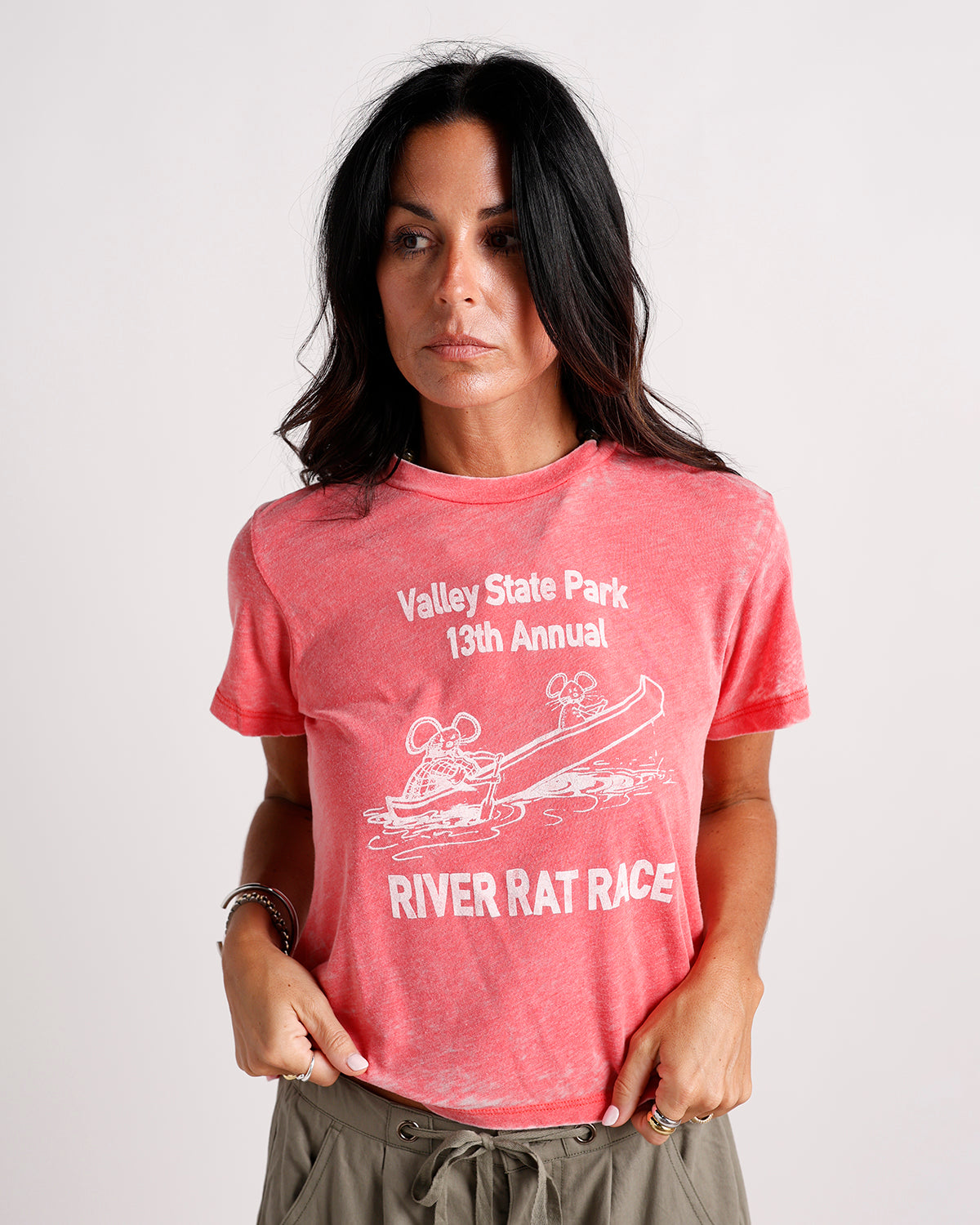 Washed red graphic tee with River Rat Race print, worn by dark-haired woman