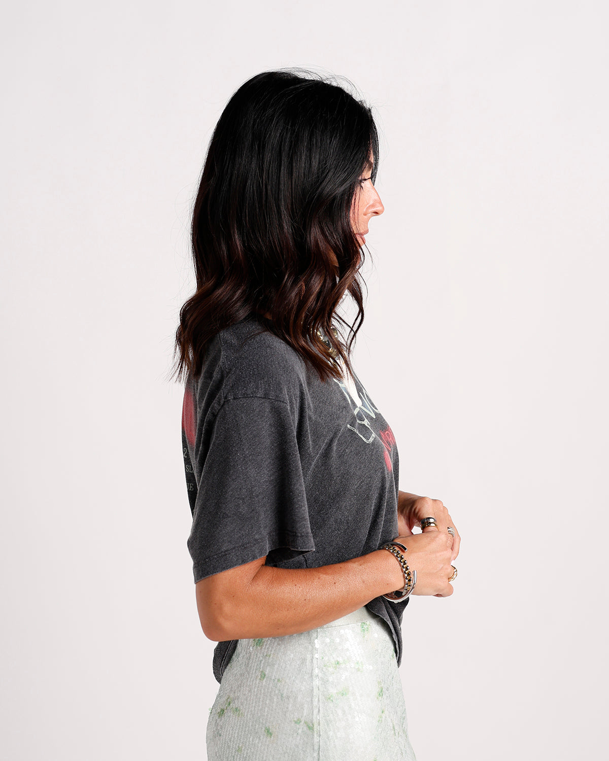 Woman wearing charcoal gray graphic tee with red print, side profile view