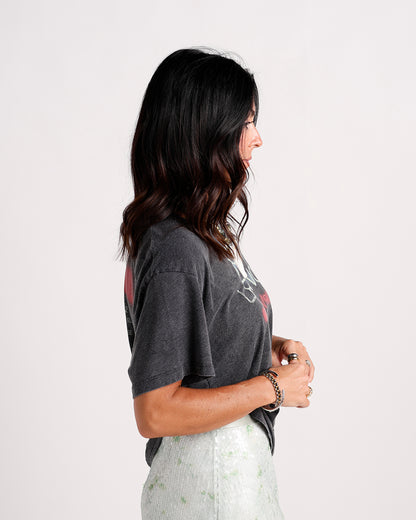 Woman wearing charcoal gray graphic tee with red print, side profile view