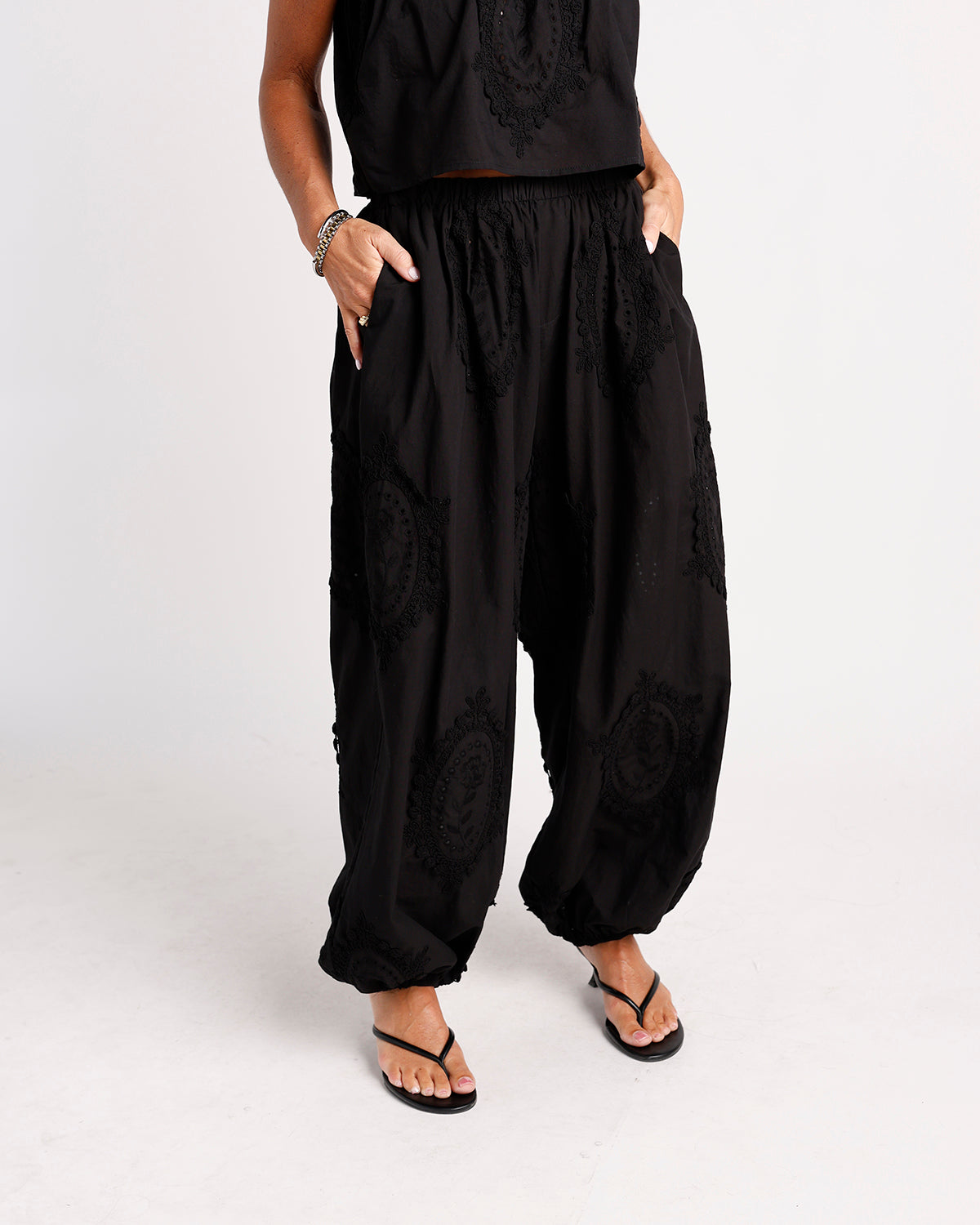 Black wide-leg harem pants with floral lace appliqué and elastic waistband