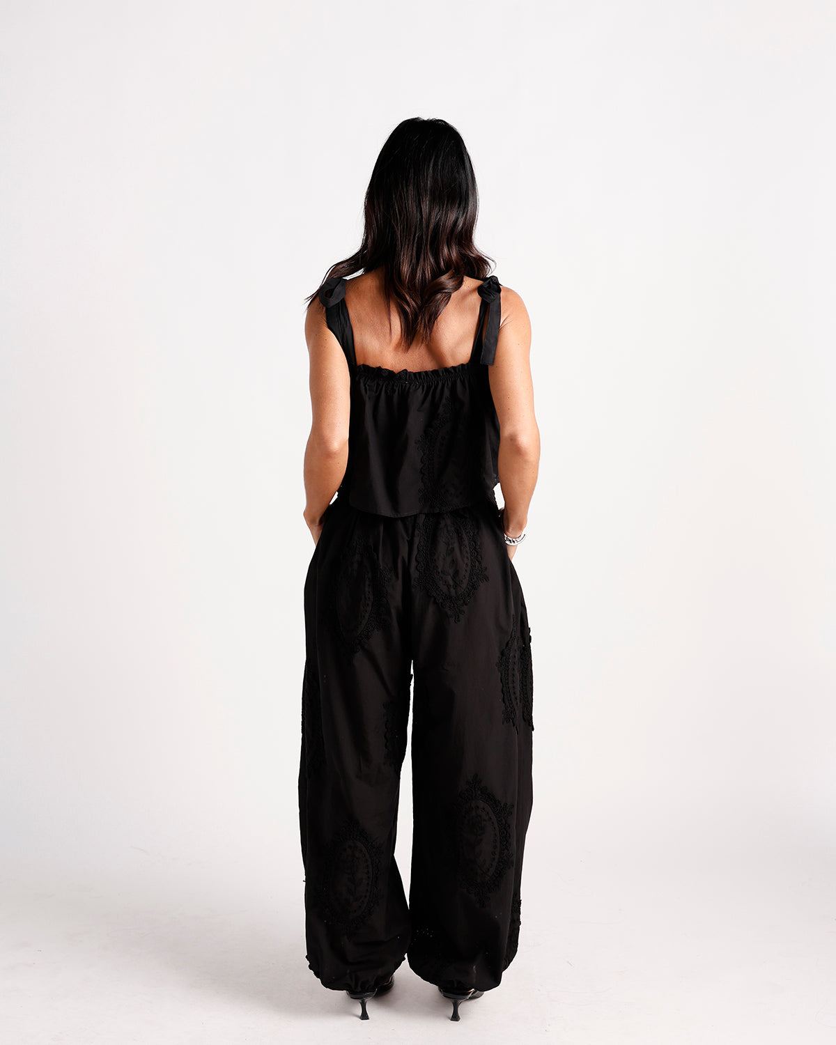 Black wide-leg dressy pants with paisley lace appliqué, elasticated hem, back view