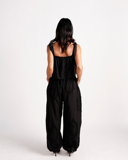 Black wide-leg dressy pants with paisley lace appliqué, elasticated hem, back view