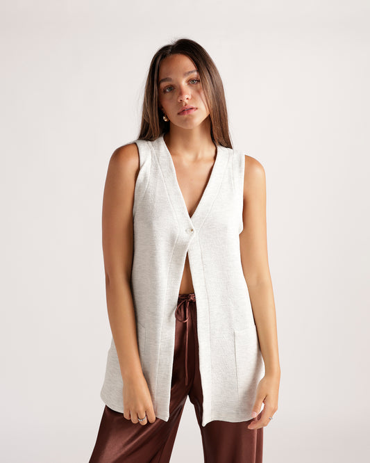 Elevate your style with this oatmeal knit sleeveless tunic top. Features a deep v-neckline, single button closure, and relaxed open hem.