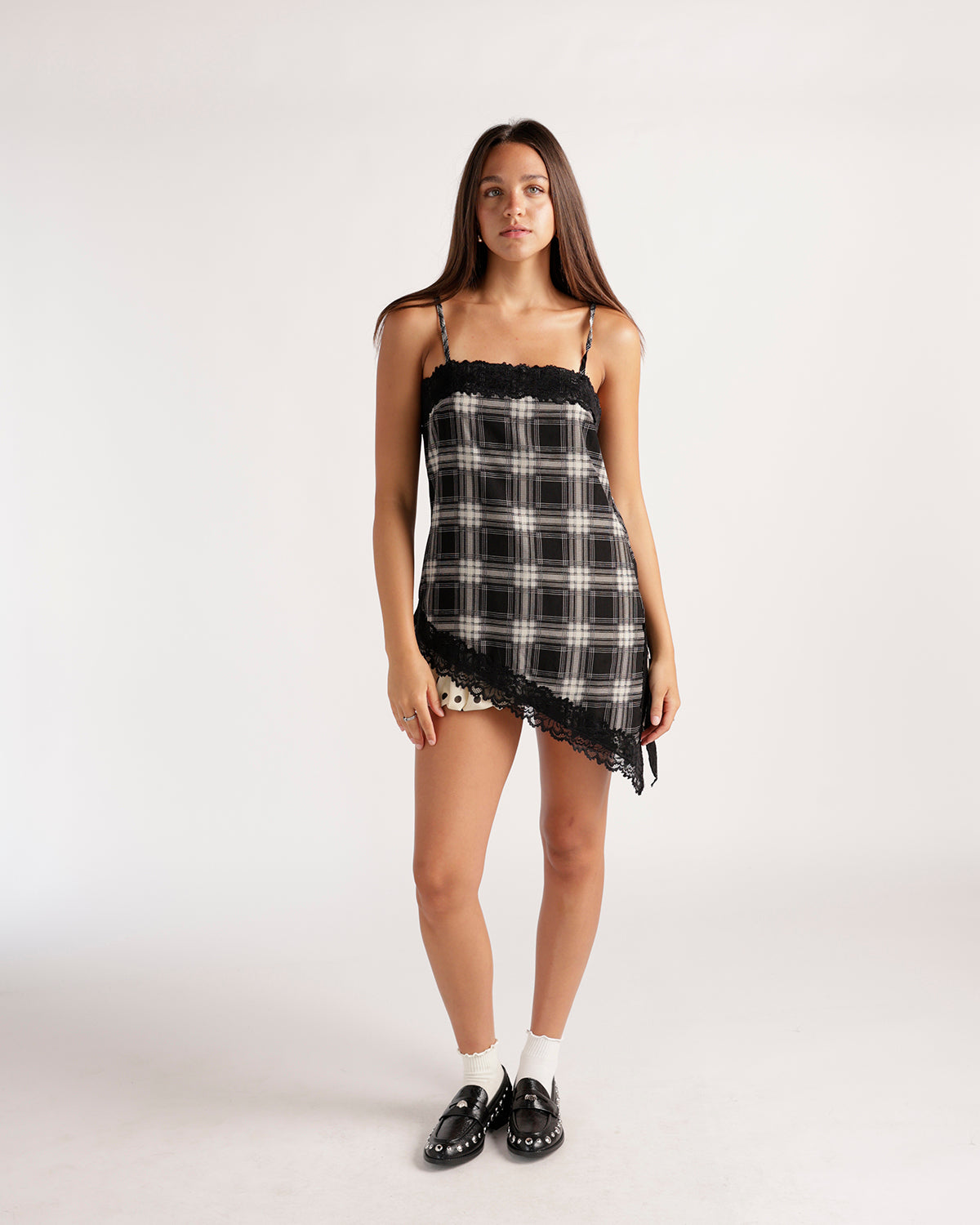 Black and white plaid asymmetrical cami with delicate black lace trim, adjustable spaghetti straps, and a flattering flowy silhouette. A chic statement top perfect for dressing up or down.