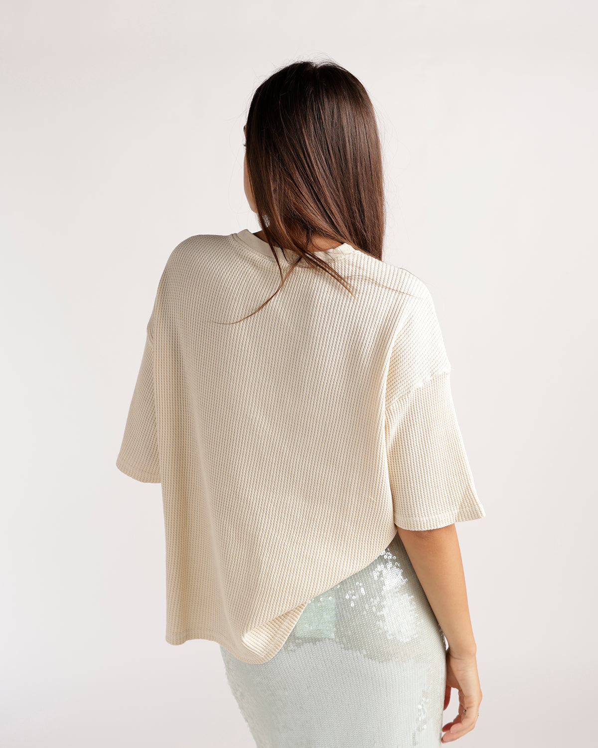 Cream ribbed oversized short-sleeve tee, back view, paired with sequin skirt.