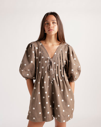 Brown and white polka dot romper featuring a flattering tie-front detail, balloon sleeves, and an easy shorts silhouette. The perfect playful romper for brunch, vacations, weekend outings, and sunny-day style.