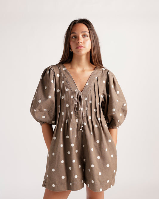 Brown and white polka dot romper featuring a flattering tie-front detail, balloon sleeves, and an easy shorts silhouette. The perfect playful romper for brunch, vacations, weekend outings, and sunny-day style.