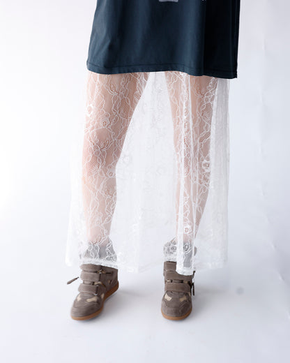 White floral lace sheer maxi skirt layered over dark top with sneakers