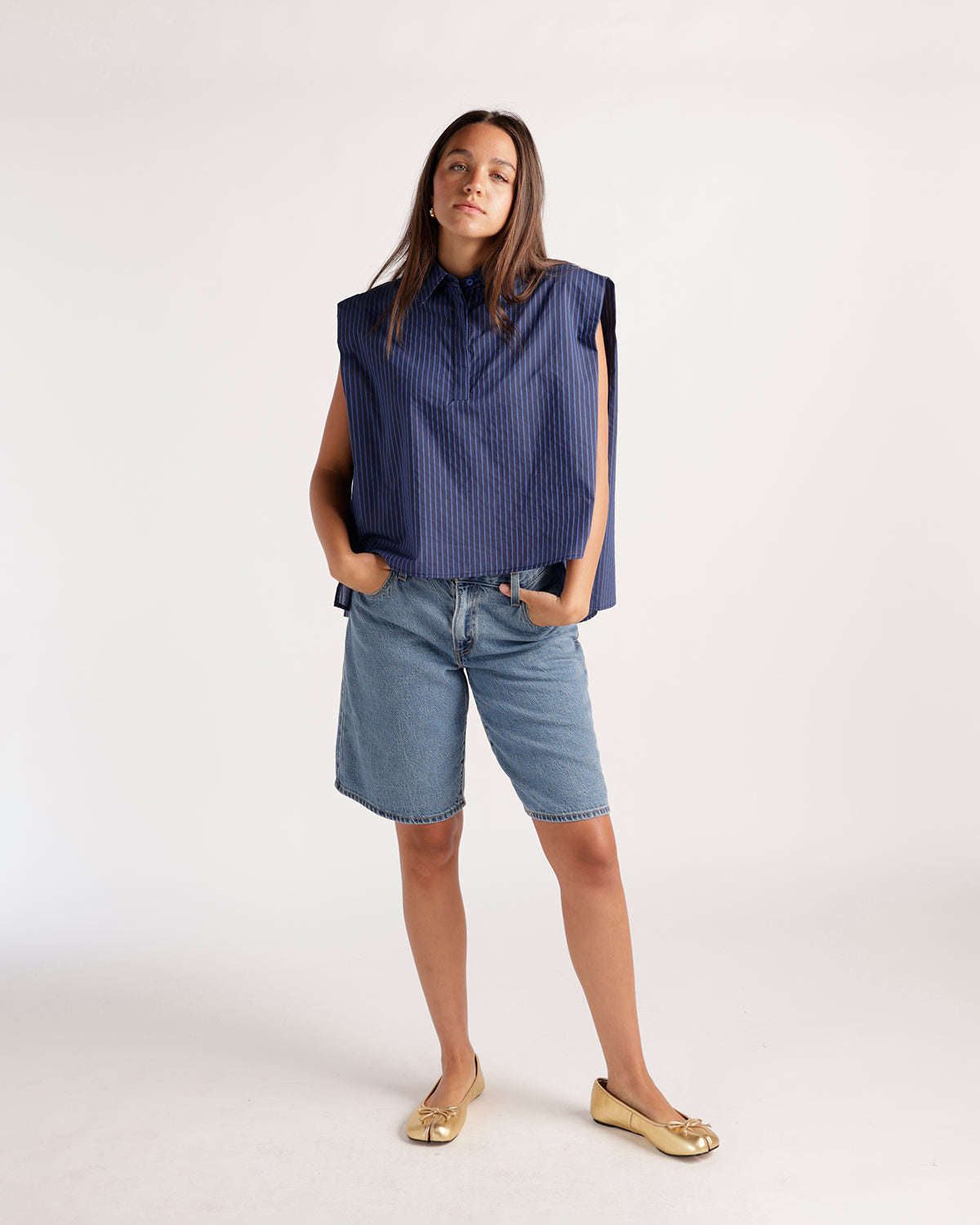Navy blue pinstripe sleeveless cropped shirt with structured shoulders and collar