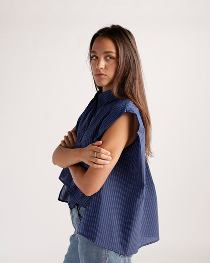 Navy blue pinstripe sleeveless top with mock neck, worn with jeans