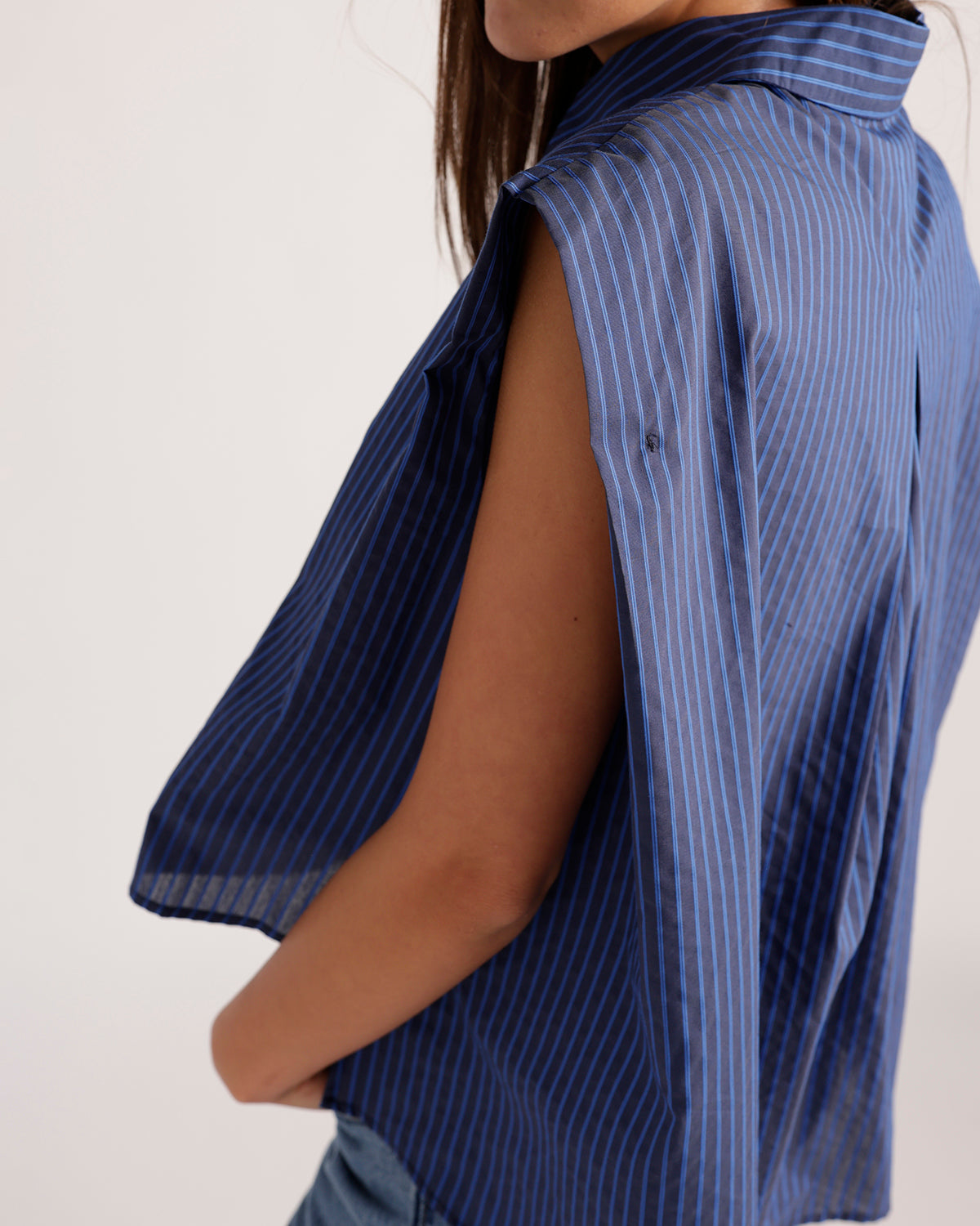 Sleeveless navy blue pinstripe button-up top with open side and collar