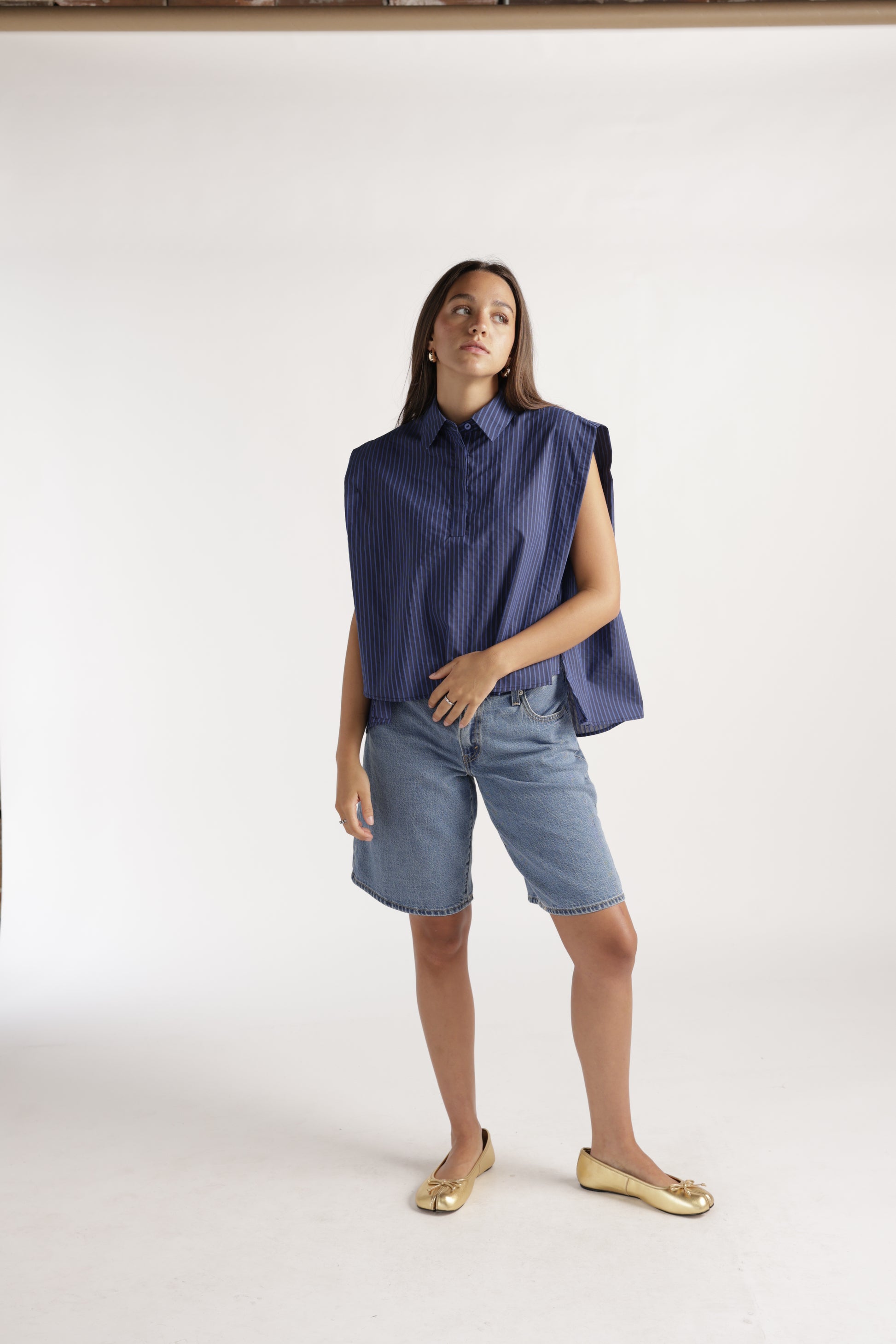 Sleeveless navy blue pinstripe button-up top with structured shoulders and collar