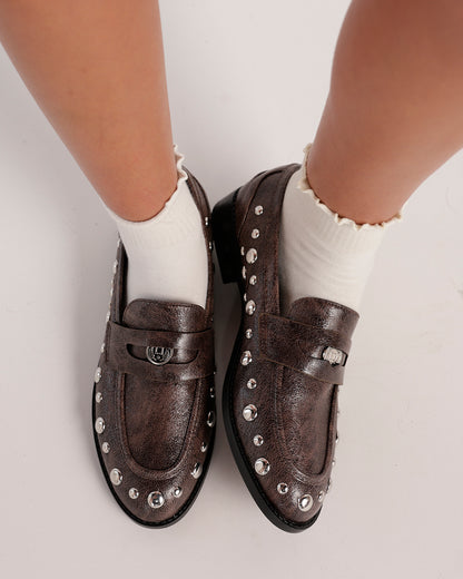 Dark taupe studded leather loafers with silver dome studs, worn with white ruffle ankle socks