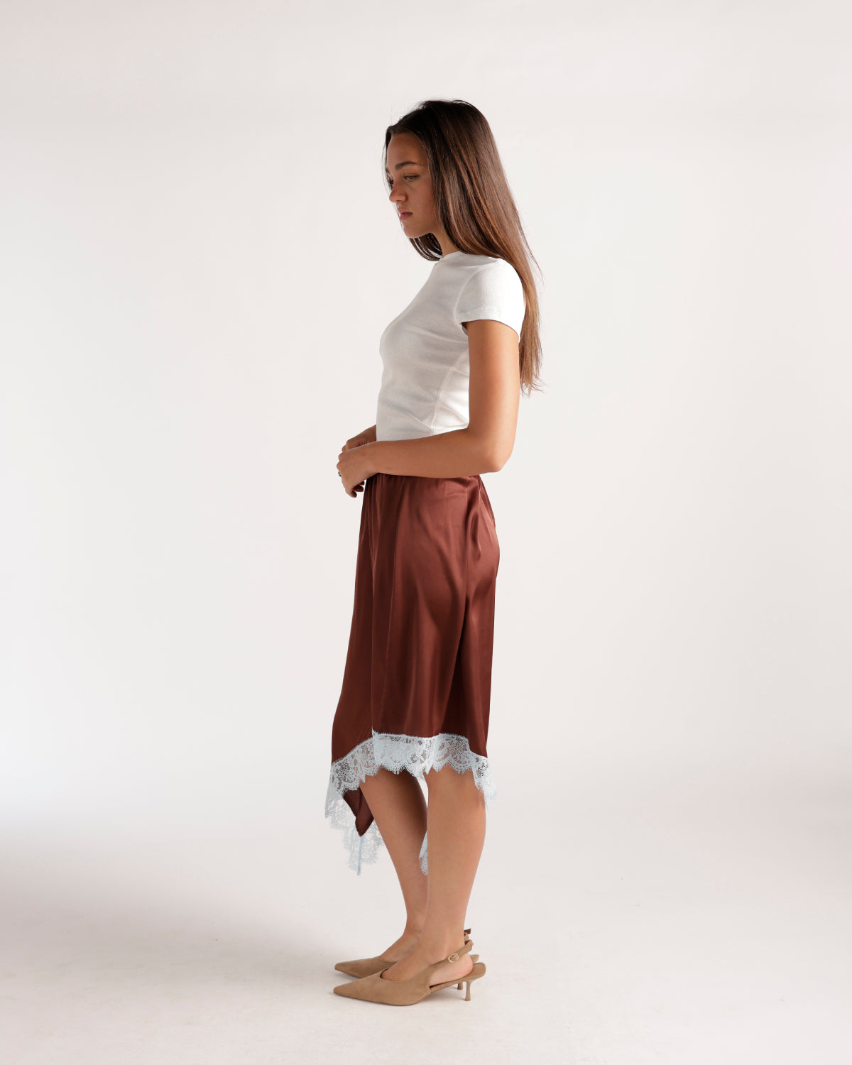 Brown satin asymmetric midi skirt with white lace hem, styled with white tee