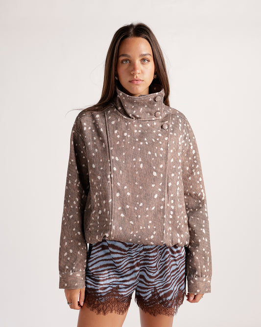 Women's brown denim jacket with a unique fawn-spot print. Trucker-style silhouette, snap-button front, and smocked hem for a feminine touch.