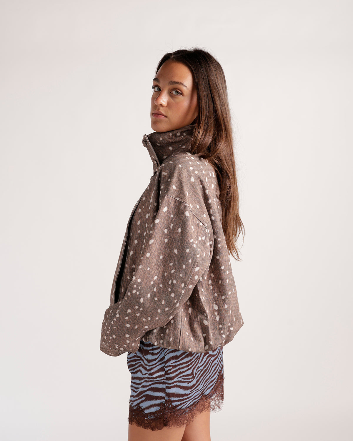 Brown spotted fawn print cropped jacket with high collar, worn over zebra print shorts.