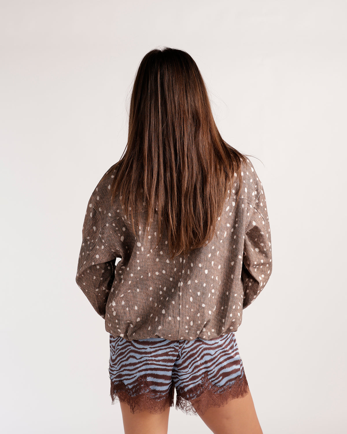 Brown spotted fawn print jacket with drop shoulders, worn over zebra print shorts