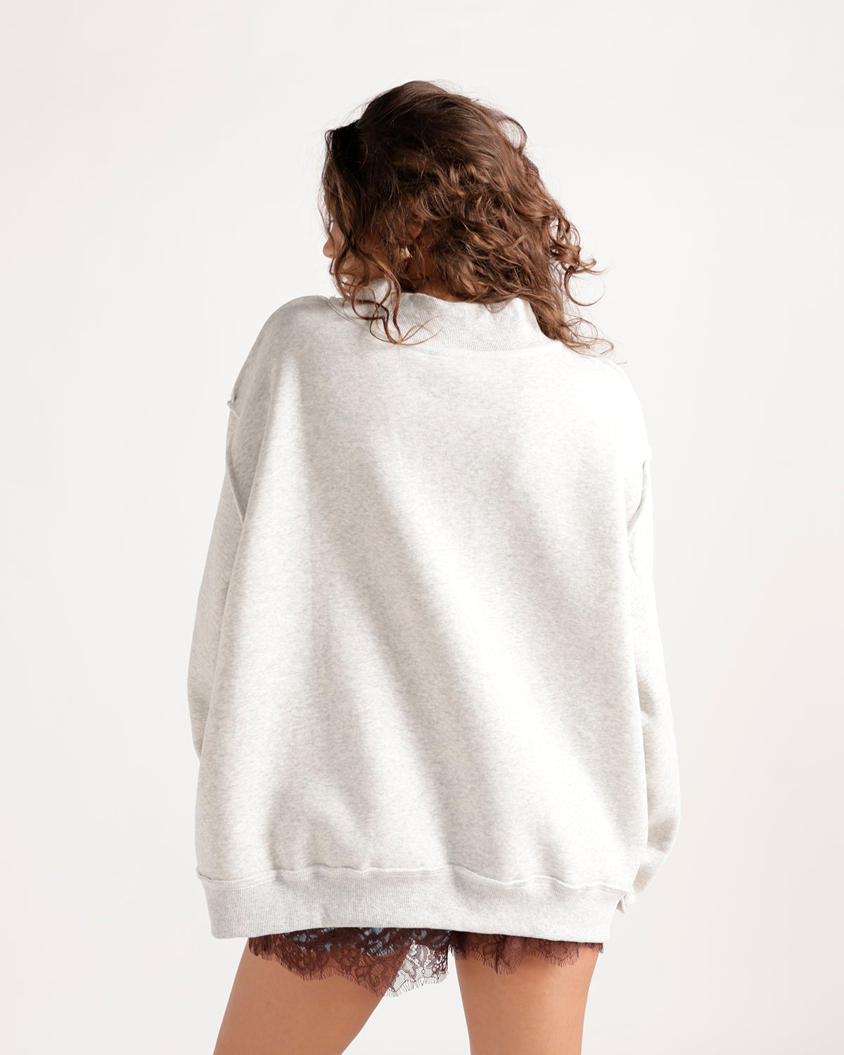 Oversized light gray mockneck sweatshirt shown from the back on a model