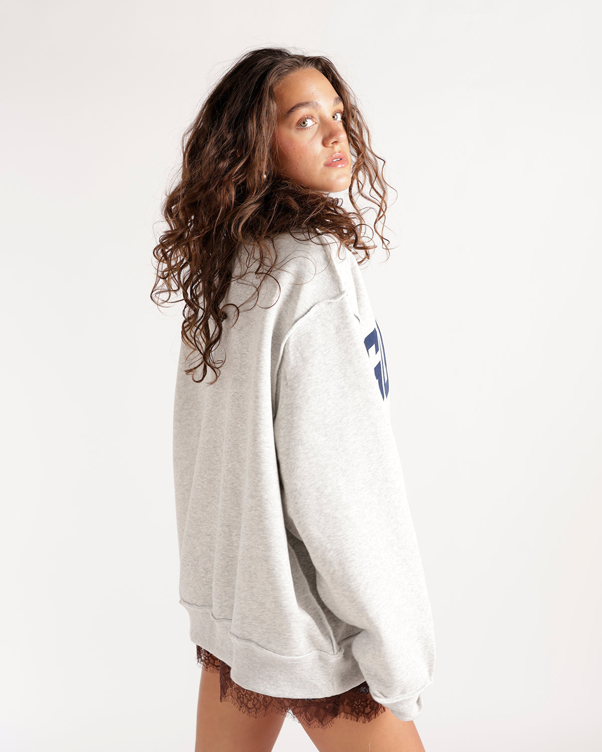 Oversized heather grey mockneck sweatshirt with navy graphic, worn over lace shorts