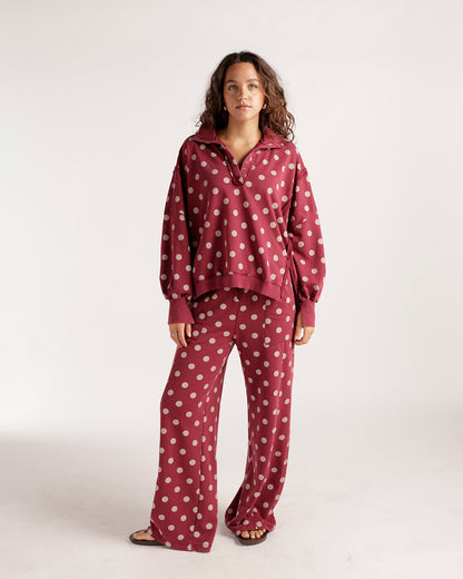 Oversized burgundy polka dot pullover with collar and snap buttons, worn with matching wide-leg pants.