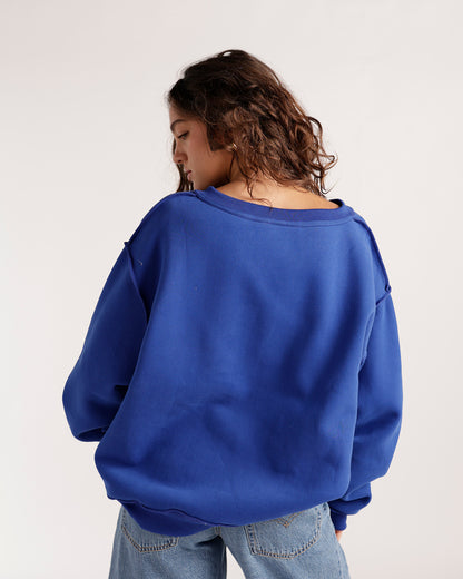 Oversized royal blue split neck reversible sweatshirt, back view, paired with jeans