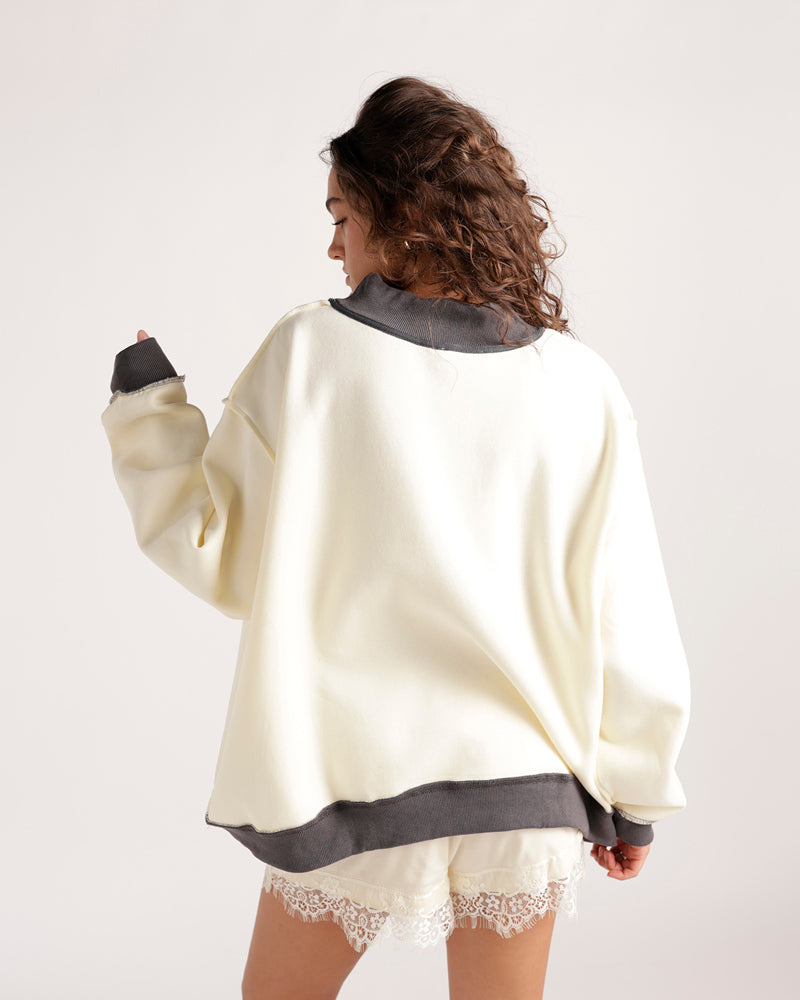 Oversized cream mockneck sweatshirt with gray contrast trim, worn with lace shorts