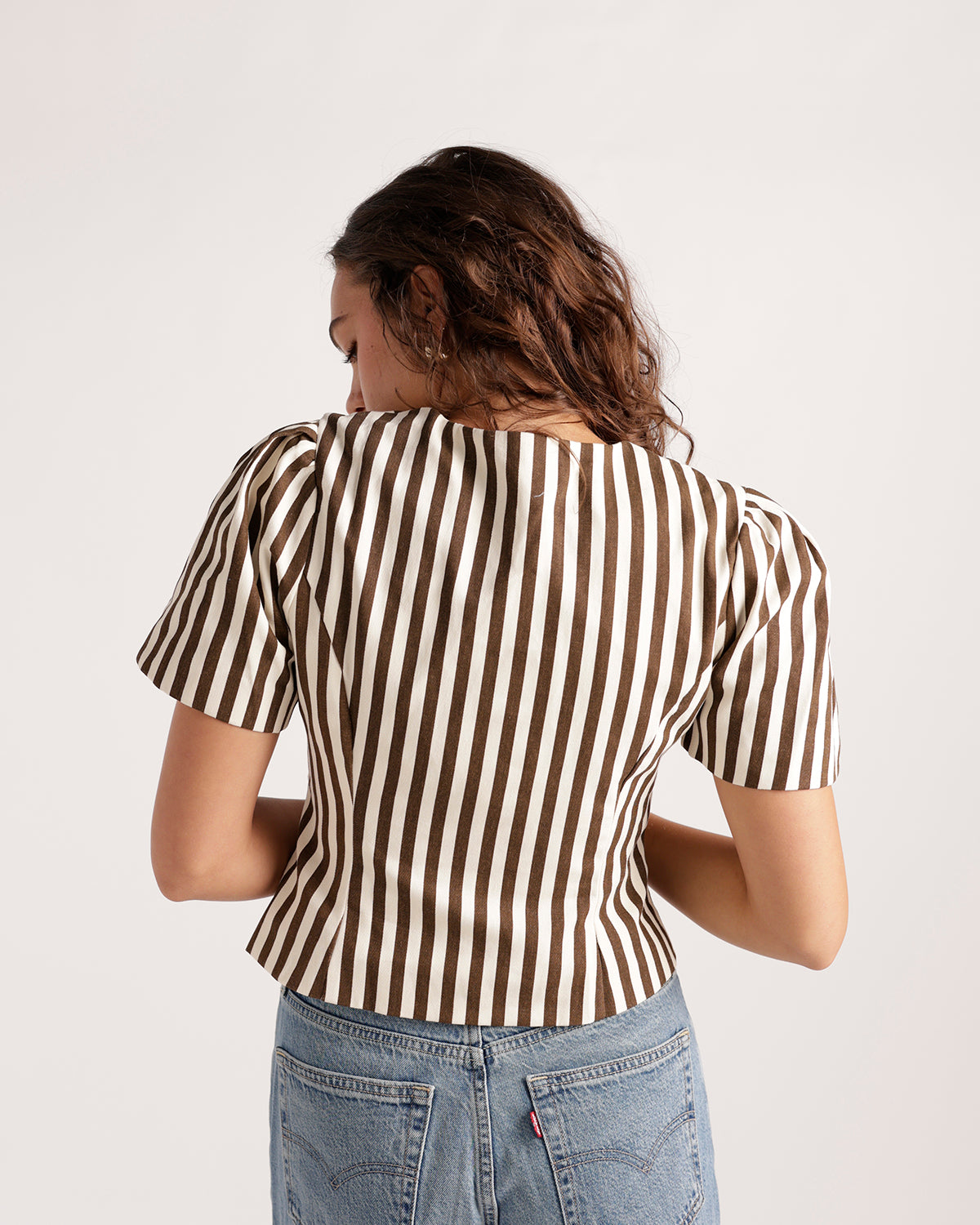 Brown and white vertical stripe short puff sleeve cropped button top, back view.