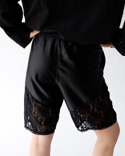 Black satin shorts with floral lace trim panels at hem, elastic waist