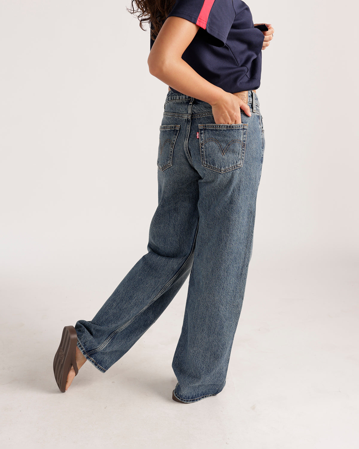 Wide-leg medium wash blue denim jeans shown from back side angle