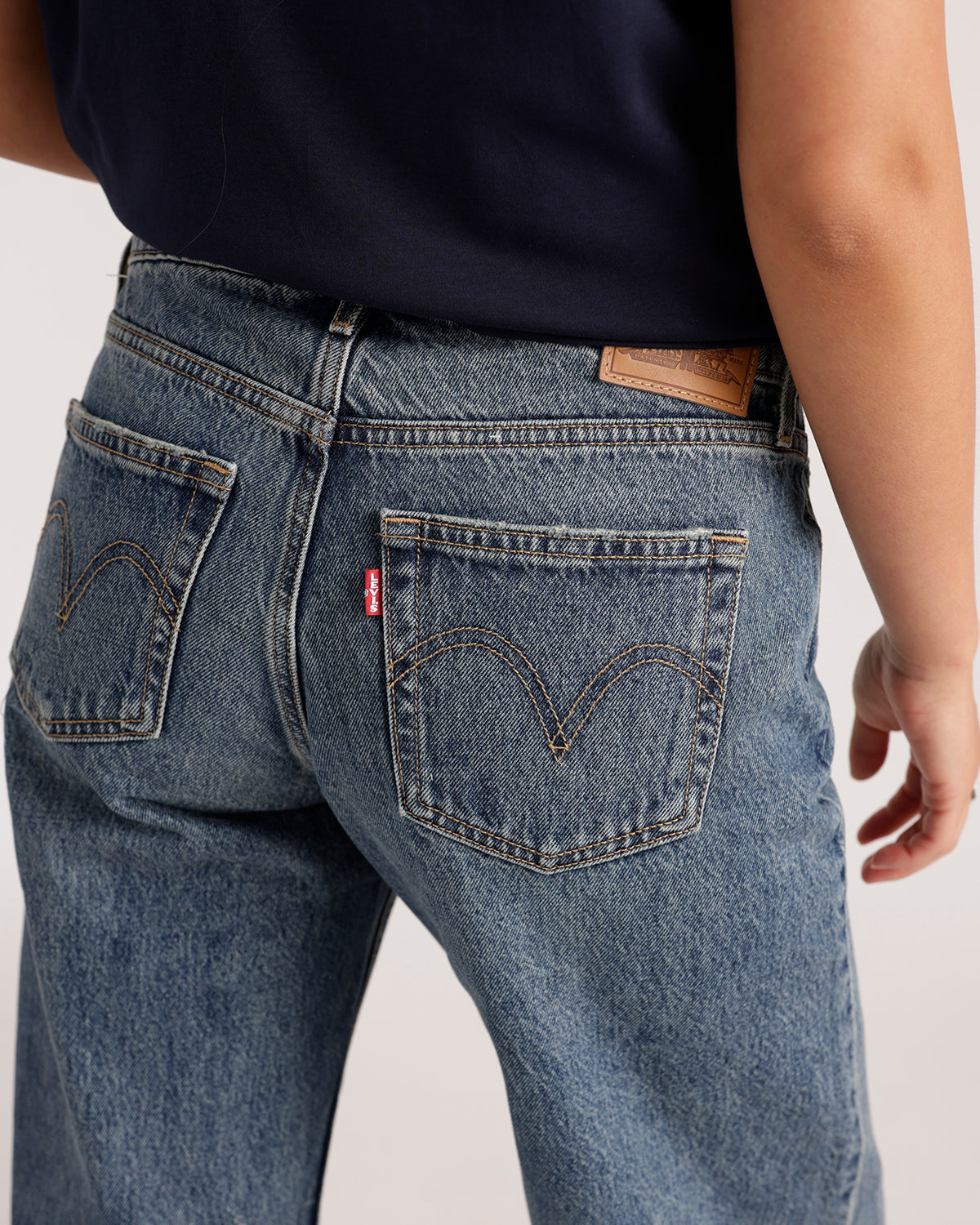 Back view of medium wash blue denim jeans with stitched arch pocket detail