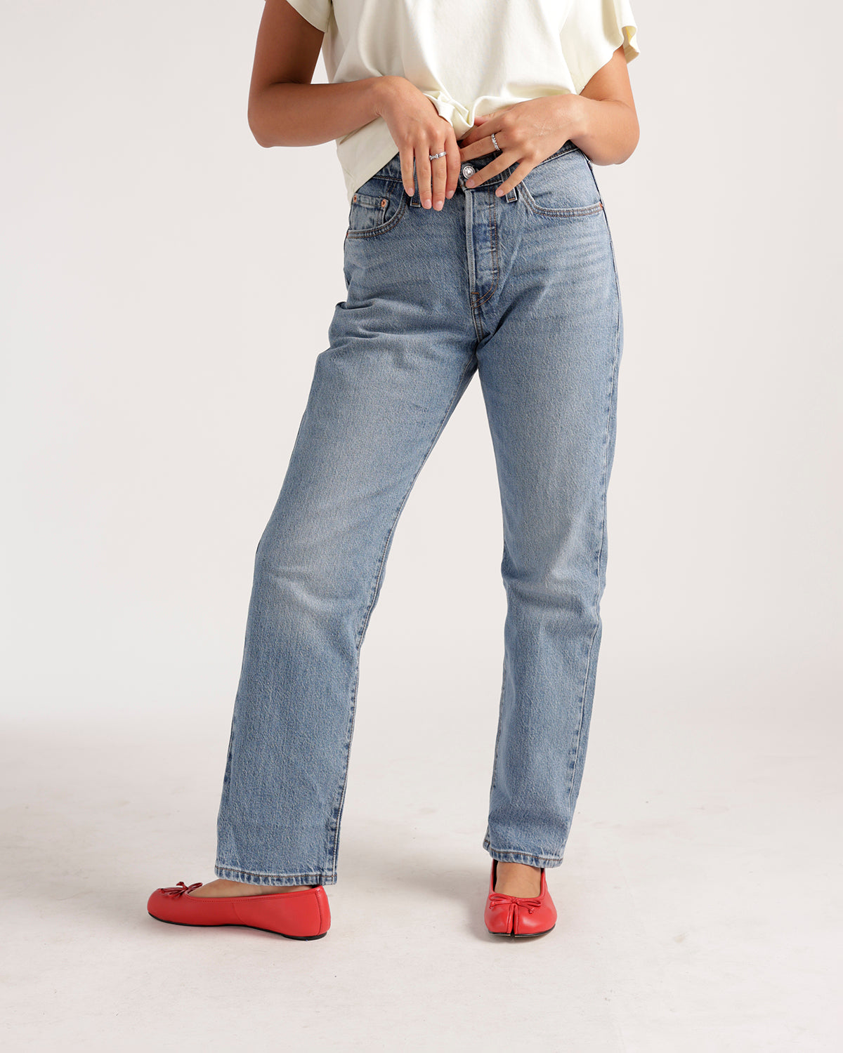 Light wash straight-leg jeans worn with red ballet flats and white top