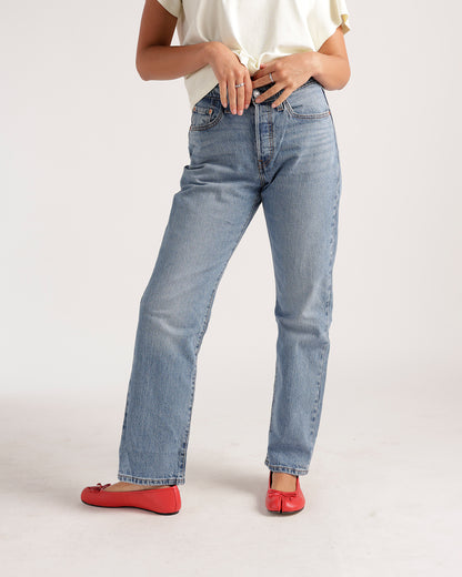Light wash straight-leg jeans worn with red ballet flats and white top