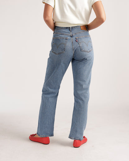 Women's light wash straight-leg jeans with classic back pockets, worn with red flats