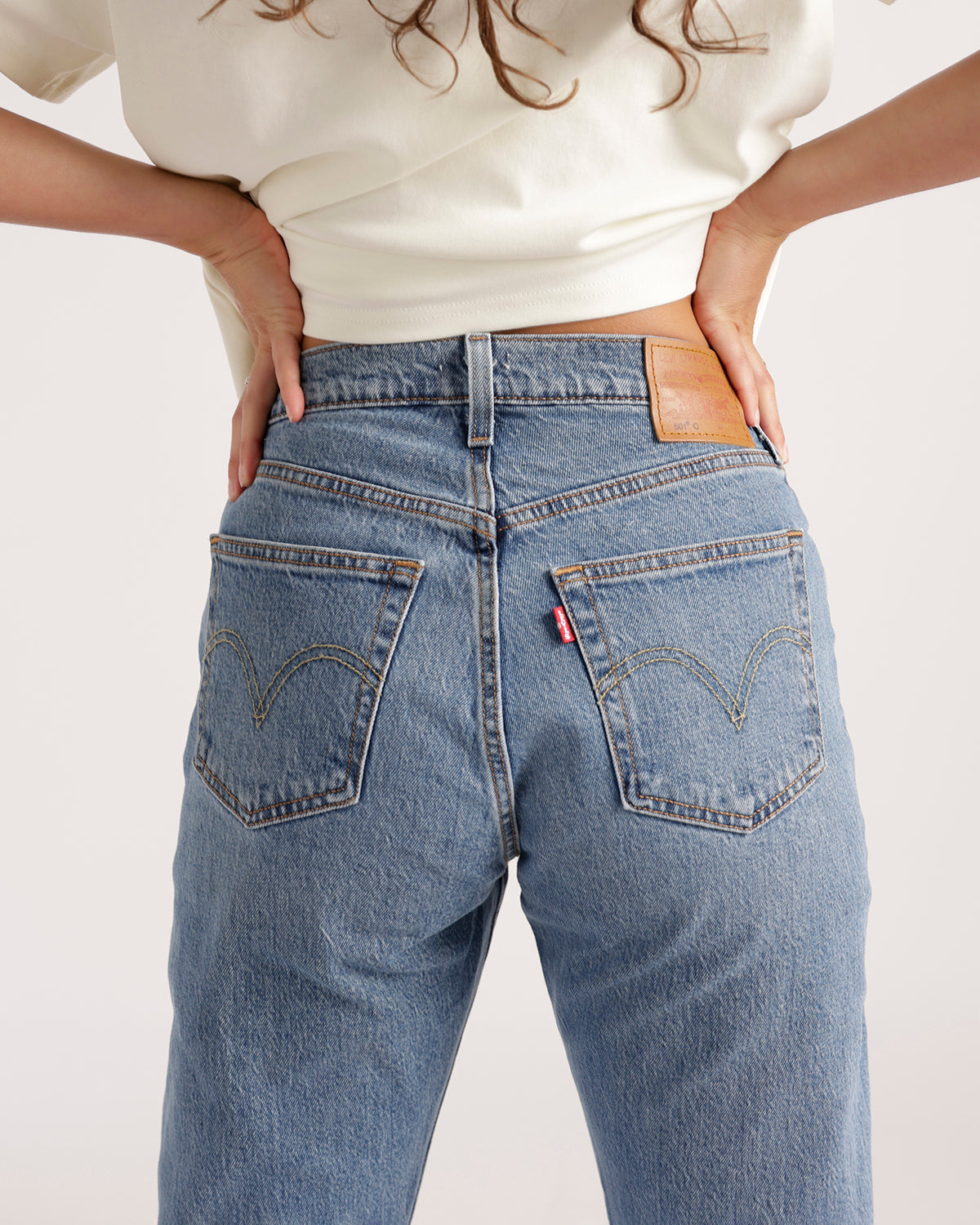 Back view of light blue wash straight-leg jeans with arc pocket stitching