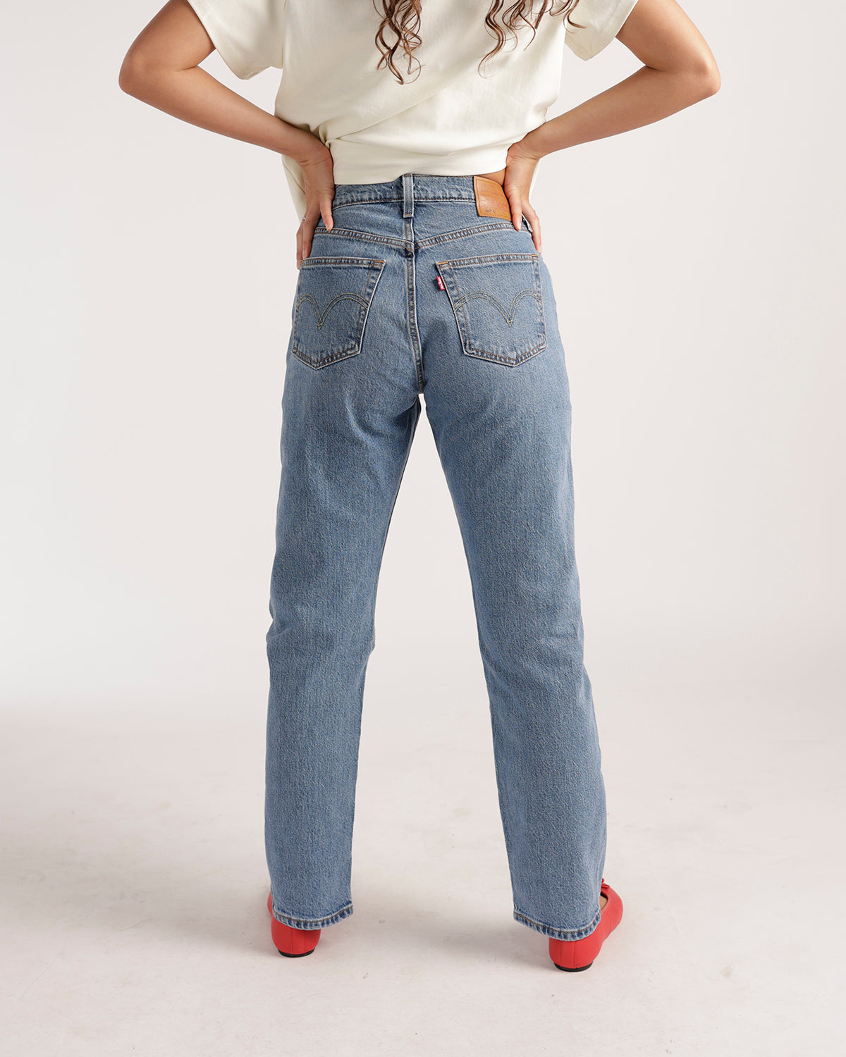 Back view of light blue straight-leg jeans with classic back pockets and gold stitching