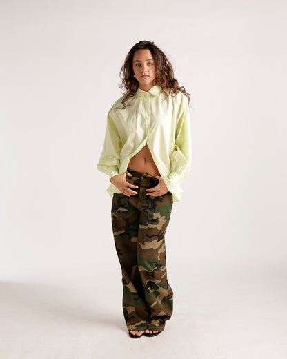 Oversized pale yellow button-up shirt with long sleeves, worn open and untucked.