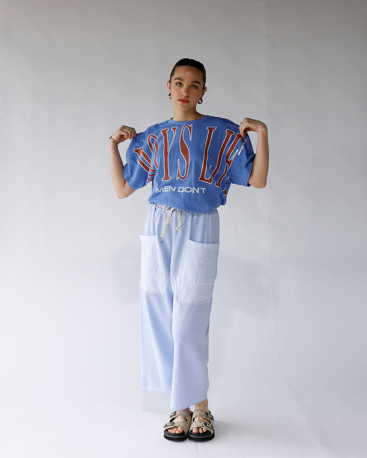 Oversized blue graphic tee with red varsity lettering, worn with light blue wide-leg pants