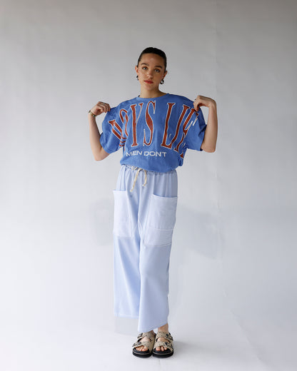 Oversized blue graphic tee with red varsity lettering, worn with light blue wide-leg pants