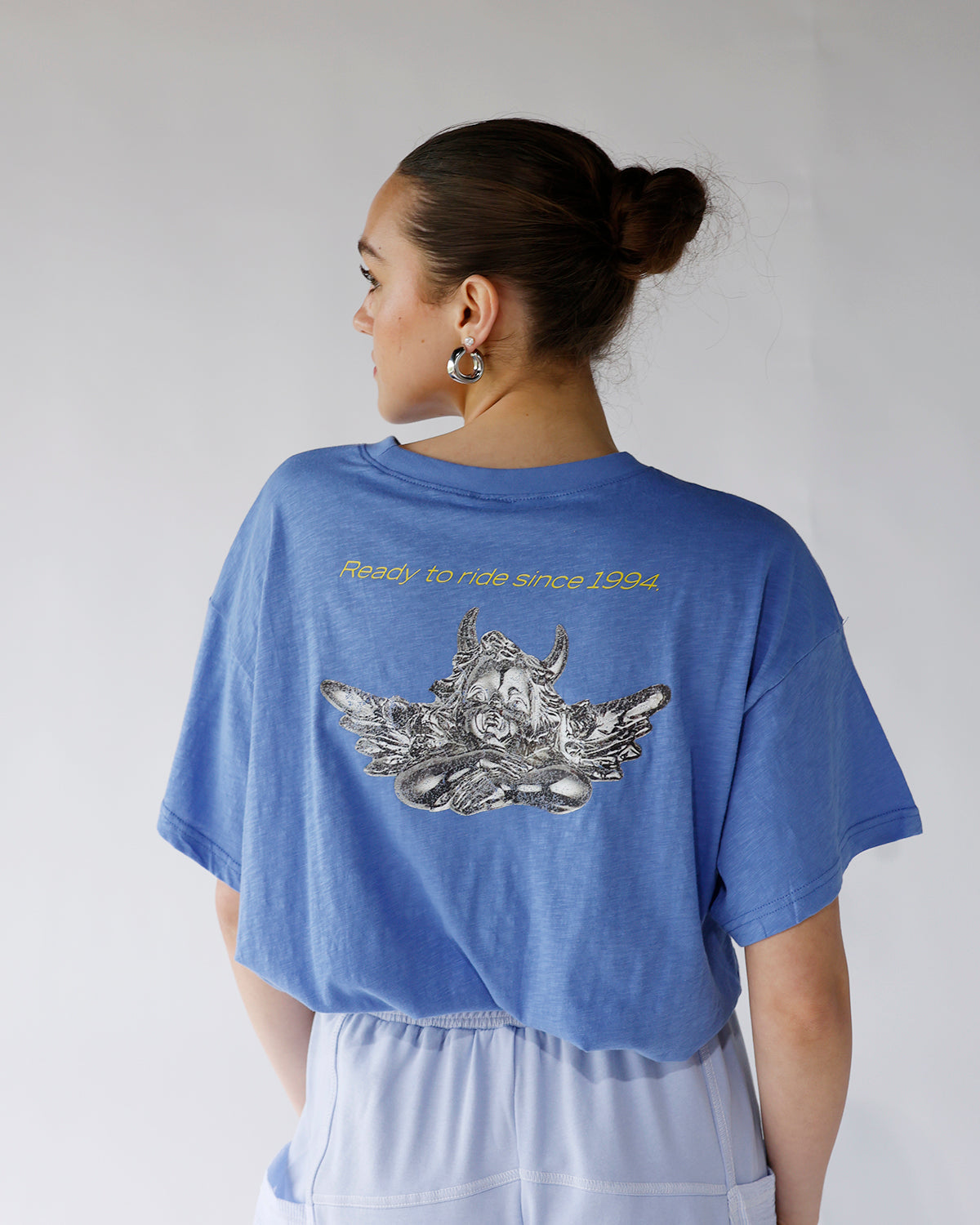 Blue oversized crop tee, back view, graphic print and yellow text detail