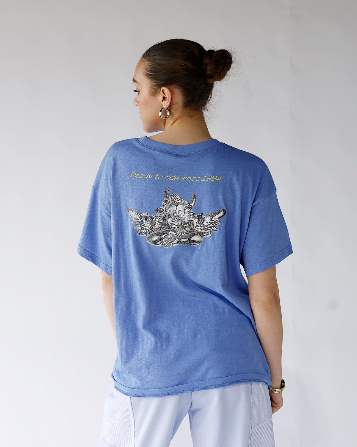 Oversized blue graphic tee with back print and yellow text, worn by model