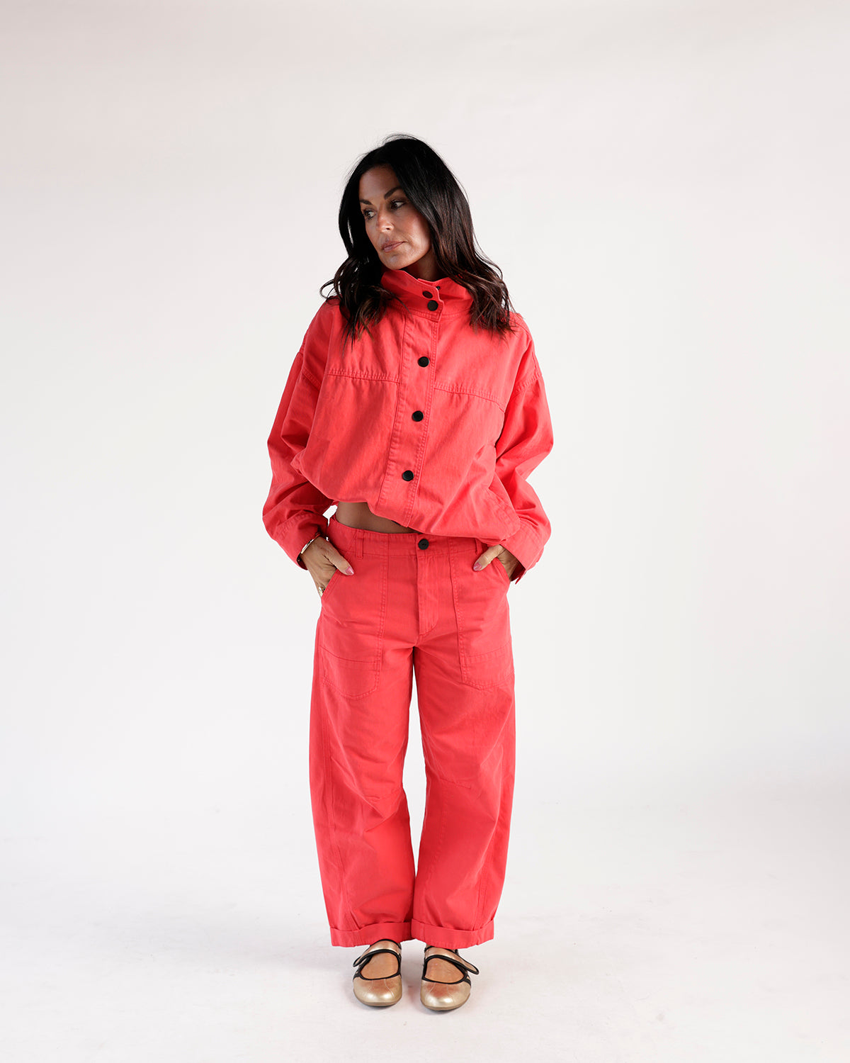 Cropped red funnel neck jacket with black buttons, worn as a matching set