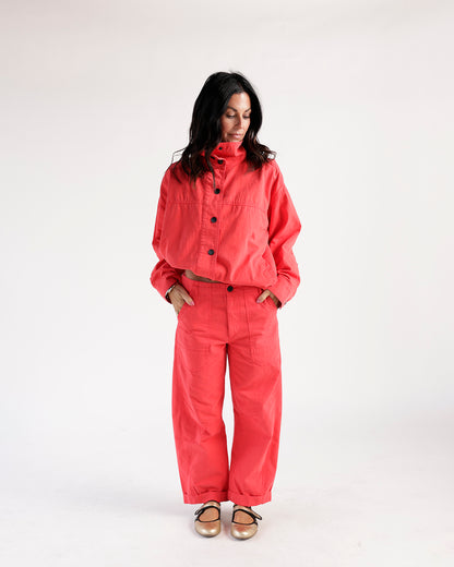 Cropped red funnel neck jacket with black buttons, worn with matching wide-leg pants