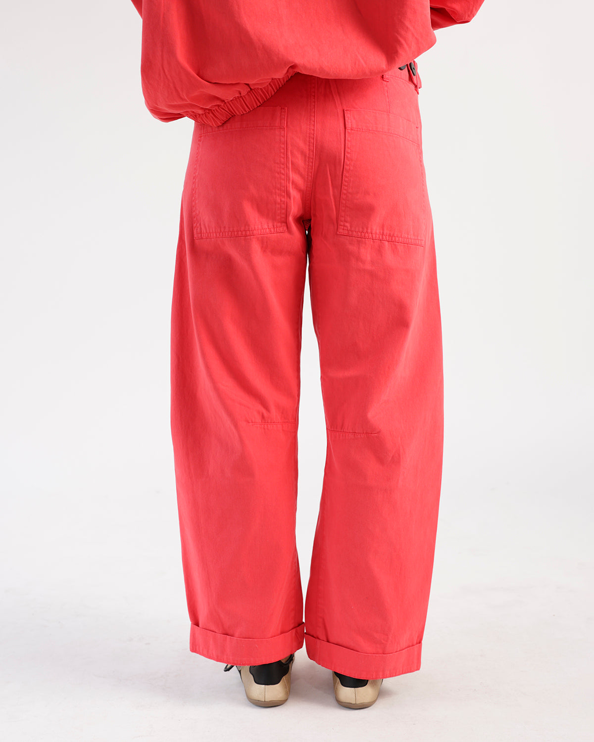 Red wide-leg utility pants with patch pockets, knee seams, and cuffed hem, back view