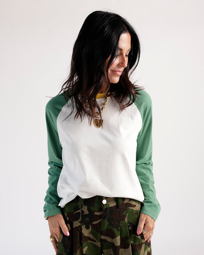 White and green raglan long-sleeve tee with yellow collar detail, worn with camo pants