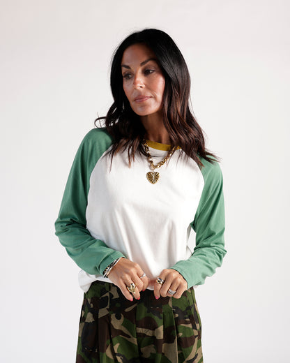 White and green raglan long-sleeve top with camouflage trousers and gold heart necklace
