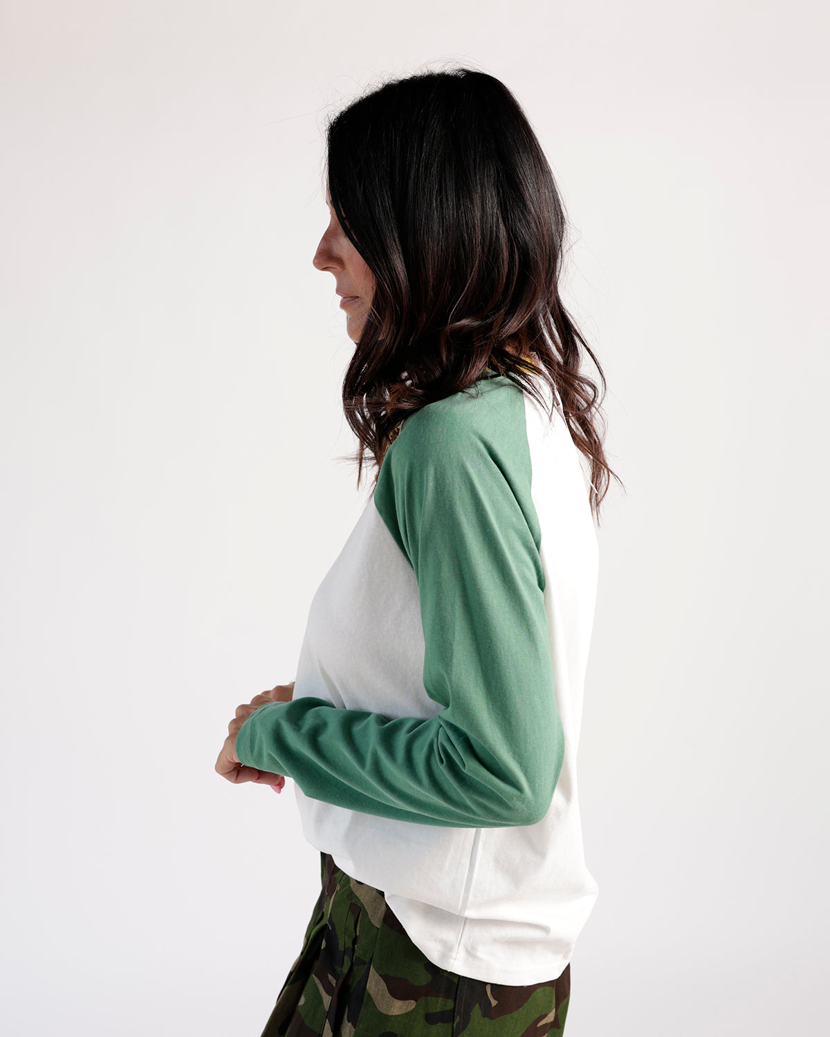 White and sage green raglan long sleeve tee, side view, paired with camo pants.