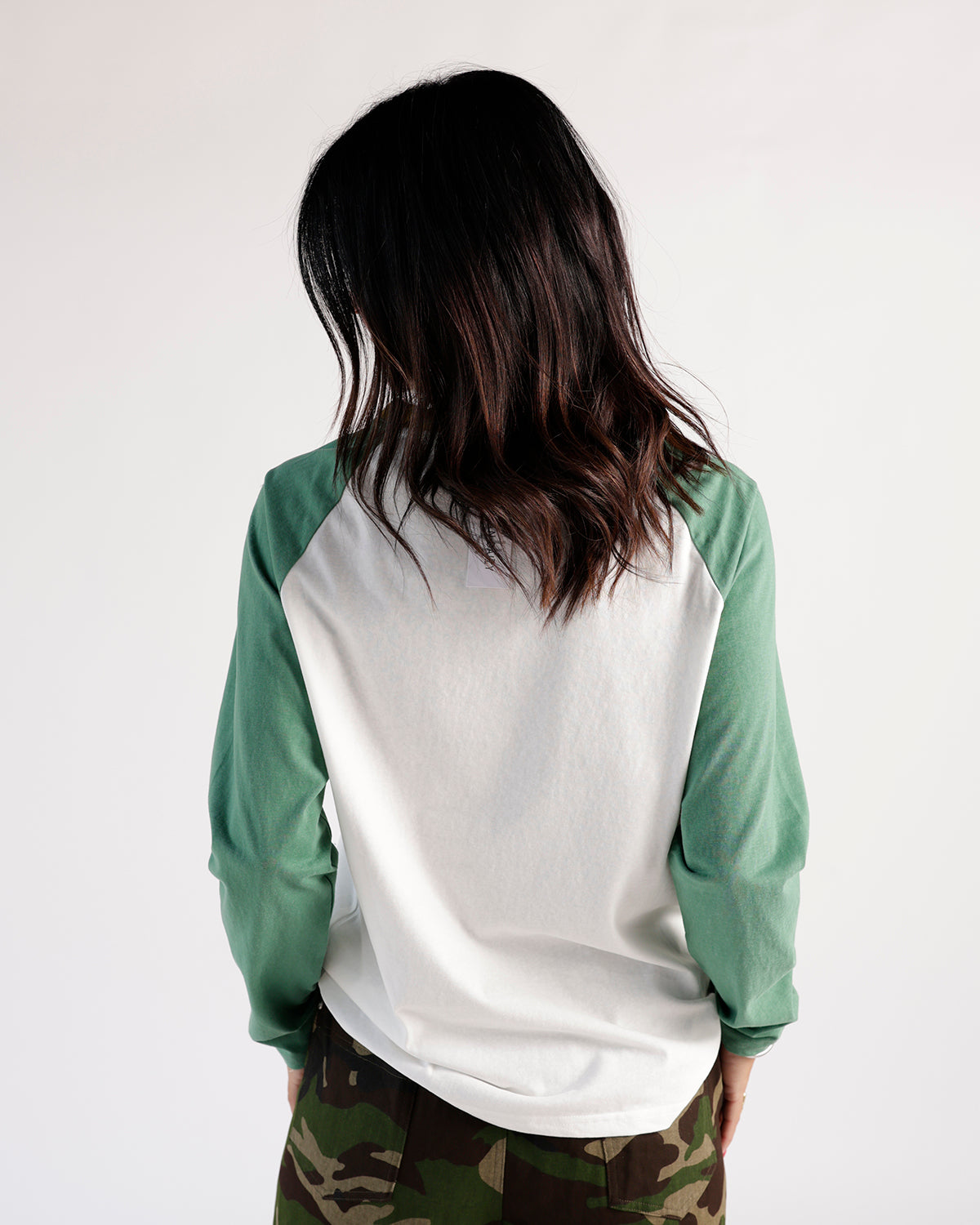 White and green raglan long sleeve shirt, back view, with camo pants