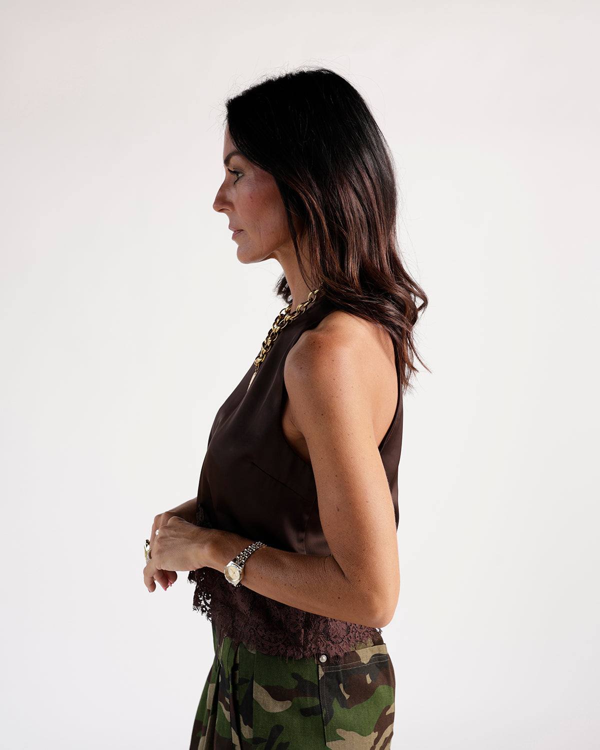 Dark brown sleeveless satin top with lace hem, worn with camo pants