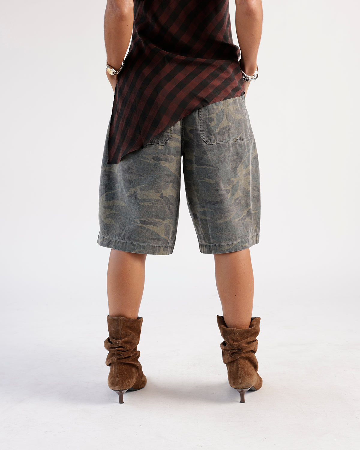 Washed camo cargo shorts in olive and gray, knee-length, worn with brown suede boots