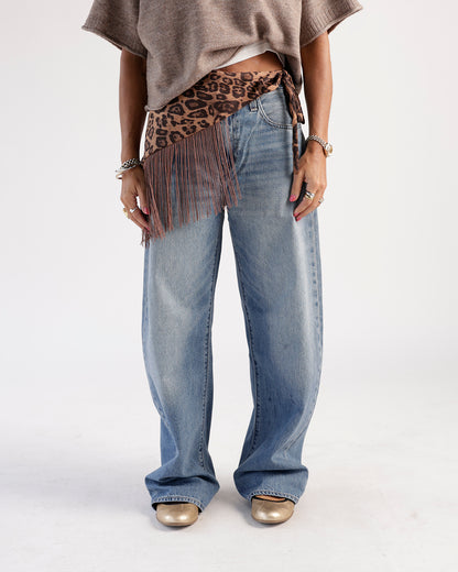 Medium wash wide-leg jeans styled with leopard fringe belt and gold flats